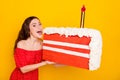Portrait of pretty positive person open mouth hold large slice of cake isolated on yellow color background