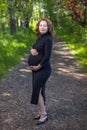 Portrait of pretty pregnant woman in a black dress green field park Royalty Free Stock Photo