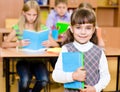 Portrait of pretty preschool girl with books in classroom