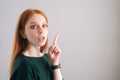 Portrait of pretty redhead young woman model pointing up with finger looking at camera on white background. Royalty Free Stock Photo