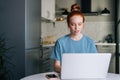 Portrait of pretty redhead young woman working typing on laptop computer sitting at table Royalty Free Stock Photo