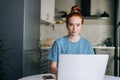 Portrait of pretty redhead young woman working typing on laptop computer sitting at table Royalty Free Stock Photo