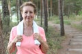 Portrait of pretty senior woman listening to music after running. Training outdoors in the morning Royalty Free Stock Photo