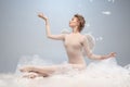 Portrait of pretty, slim beautiful young girl, graceful ballerina in image of angel with wings sitting on cloud isolated Royalty Free Stock Photo