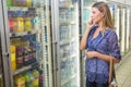 Portrait of a pretty smiling blonde woman buying frozen products and phoning Royalty Free Stock Photo