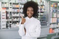 Portrait of pretty smiling confident African American female pharmacist in modern drugstore, looking at camera and Royalty Free Stock Photo