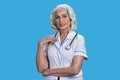 Portrait of pretty smiling senior female doctor with stethoscope on blue background. Royalty Free Stock Photo