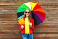 Portrait pretty smiling woman with colorful umbrella in autumn with maple leafs over wooden background wearing red leather jacket Royalty Free Stock Photo