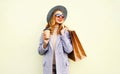 Portrait pretty smiling woman with shopping bags, holding coffee cup, wearing pink coat, round hat Royalty Free Stock Photo
