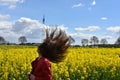 Girl in canola field wit flying brown hair Royalty Free Stock Photo