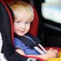 Portrait of pretty toddler boy sitting in car seat