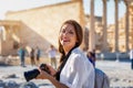 Portrait of a pretty tourist woman with a photo camera in her hand in front of the Acropolis of Athens, Greece