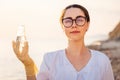 Portrait of pretty woman ecologist wearing protective gloves and eyeglasses, holds test sample flask of pure water from