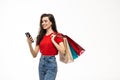 Portrait of a pretty woman holding shopping bags while using mobile phone isolated over white background Royalty Free Stock Photo