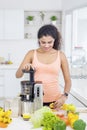 Pretty woman making juice with juicer machine Royalty Free Stock Photo