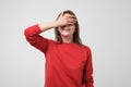 Portrait of pretty woman in red sweater closing her eyes with palm. She is waiting for surprise or gift. Royalty Free Stock Photo