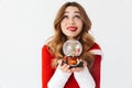 Portrait of pretty woman 20s wearing Santa Claus red costume smiling and holding Christmas snow ball, isolated over white Royalty Free Stock Photo