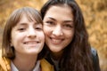 Portrait of pretty woman and teen girl. They are posing in autumn park. Beautiful landscape at fall season Royalty Free Stock Photo