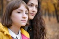 Portrait of pretty woman and teen girl. They are posing in autumn park. Beautiful landscape at fall season Royalty Free Stock Photo