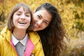 Portrait of pretty woman and teen girl. They are posing in autumn park. Beautiful landscape at fall season Royalty Free Stock Photo