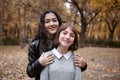 Portrait of pretty woman and teen girl. They are posing in autumn park. Beautiful landscape at fall season Royalty Free Stock Photo