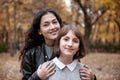 Portrait of pretty woman and teen girl. They are posing in autumn park. Beautiful landscape at fall season Royalty Free Stock Photo