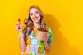 Portrait of pretty woman wear flower print t-shirt hand hold strawberry look at offer empty space isolated on yellow