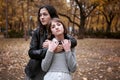 Portrait of pretty woman and teen girl. They are posing in autumn park. Beautiful landscape at fall season Royalty Free Stock Photo