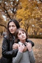 Portrait of pretty woman and teen girl. They are posing in autumn park. Beautiful landscape at fall season Royalty Free Stock Photo