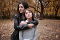 Portrait of pretty woman and teen girl. They are posing in autumn park. Beautiful landscape at fall season Royalty Free Stock Photo