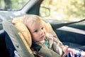 Portrait of pretty 1 year old toddler boy sitting in car safety seat mounted in the front seat. Child transportation safety