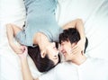 Portrait of pretty young asian couple with happiness. asia man and woman lay on bed facing together with big smile hand cover face Royalty Free Stock Photo