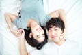 Portrait of pretty young asian couple with happiness. asia man and woman lay on bed facing together with big smile hand cover face Royalty Free Stock Photo