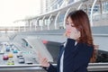 Portrait of pretty young Asian lady secretary talking on phone and looking paperwork in ring binder at urban city with sunshine ef Royalty Free Stock Photo