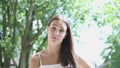 portrait pretty young brunette female with long hair and white top green trees