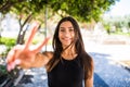 Portrait pretty young brunette smiling shows victory sign background summer green park outdoors Royalty Free Stock Photo