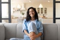 Portrait of pretty young brunette woman smiling and looking at camera, sitting on couhc at home Royalty Free Stock Photo