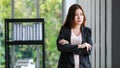 Portrait of pretty young business woman in casual black suit standing in the office with crossed arms, happy smiling and looking Royalty Free Stock Photo