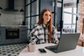 Portrait of pretty young business woman remote working or studying on laptop computer sitting at table, holding in hand Royalty Free Stock Photo