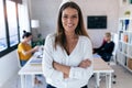 Pretty young businesswoman looking at camera. In the background, her colleagues working in the office Royalty Free Stock Photo