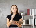 portrait of pretty young caucasian woman thinking with pen and tablet in hands, book shelf with copy space at background. pretty Royalty Free Stock Photo