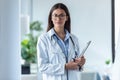 Pretty young female doctor looking at camera while standing in the office Royalty Free Stock Photo