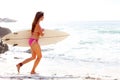 Professional female surfer going for surfing. Portrait of a pretty young female running with a surfboard towards sea. Royalty Free Stock Photo