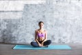 Portrait of a pretty young fitness girl sitting on a mat intdoors