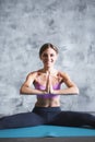 Portrait of a pretty young fitness girl sitting on a mat intdoors