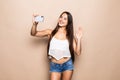 Portrait of a pretty young girl taking selfie with mobile phone and waving isolated over beige background Royalty Free Stock Photo