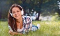 Portrait of pretty young girl listening music lying at the grass Royalty Free Stock Photo