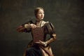 Portrait of pretty young girl, medieval royal person, princess in vintage dress holding giant chocolate bar against dark