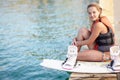 Portrait of a pretty young girl sitting on a jetty next to a wakeboard. Portrait of a pretty young girl sitting on a Royalty Free Stock Photo