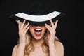 Pretty young happy blonde woman with bright makeup red lips posing isolated over black wall background wearing hat Royalty Free Stock Photo